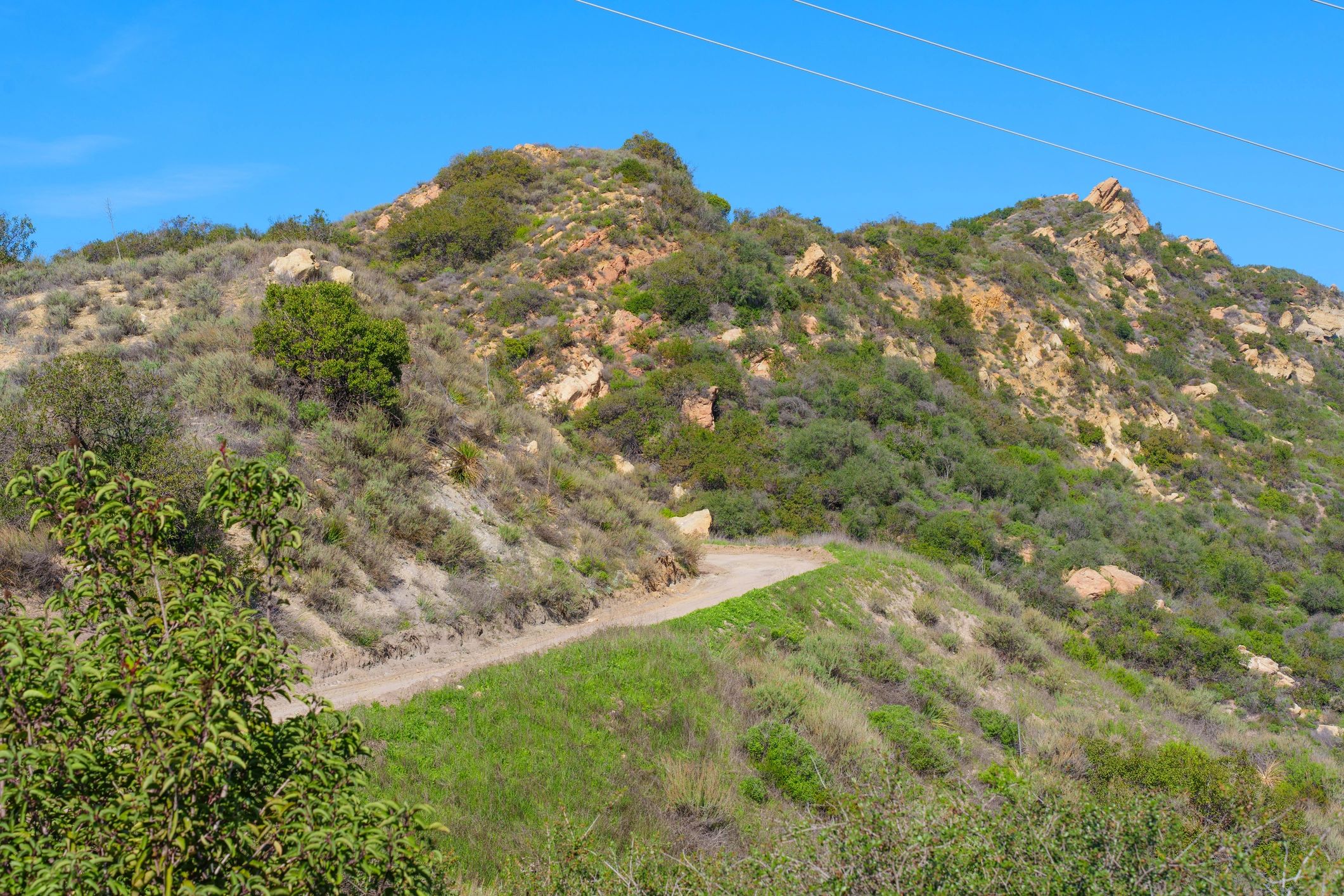 Open trail through rugged hills under clear sky